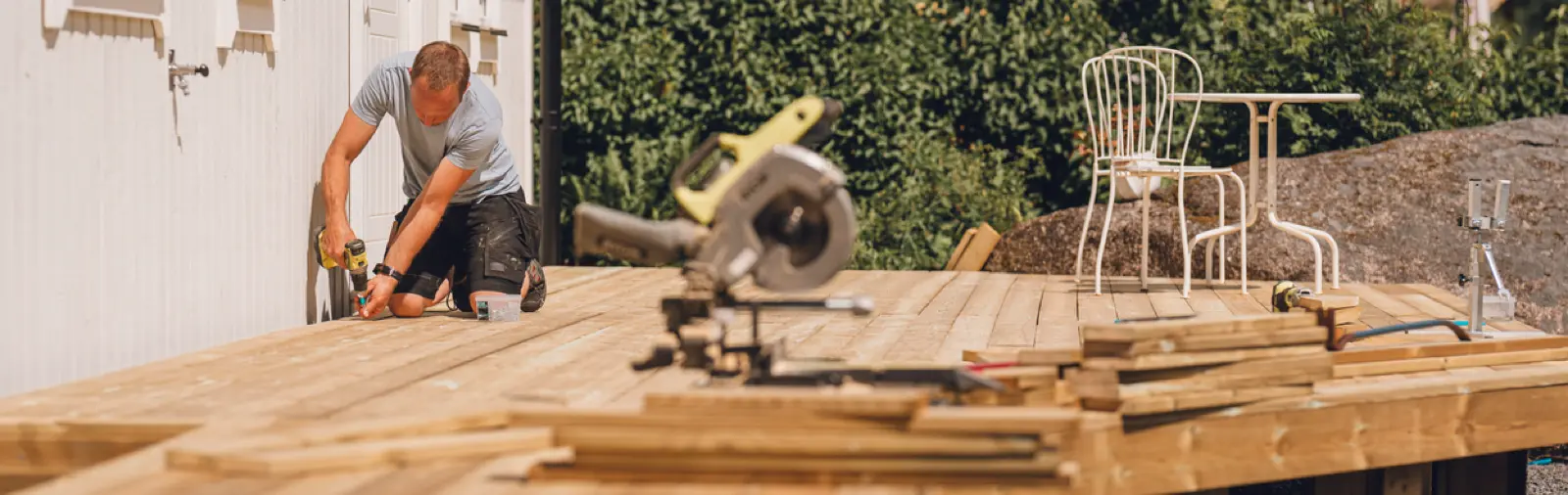 Person building a wooden deck with power tools